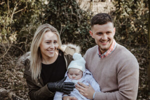 Family photo af Mum, Dad and bay outside taken by Sophie Ransome Mum and bay wrapped up outside during family session with Sophie Ransome Lifestyle Photographer