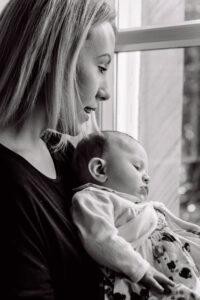 Mum and baby girl look out of the window by Sophie Ransome Lifestyle Photographer