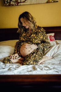 Mum to be sits on the bed, maternity photography by Sophie Ransome Lifestyle Photographer