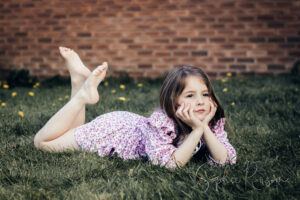 A portrait of a girl daydreaming on the grass by Sophie Ransome Lifestyle Photographer
